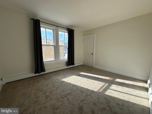 spare room featuring a baseboard radiator, baseboards, and carpet flooring