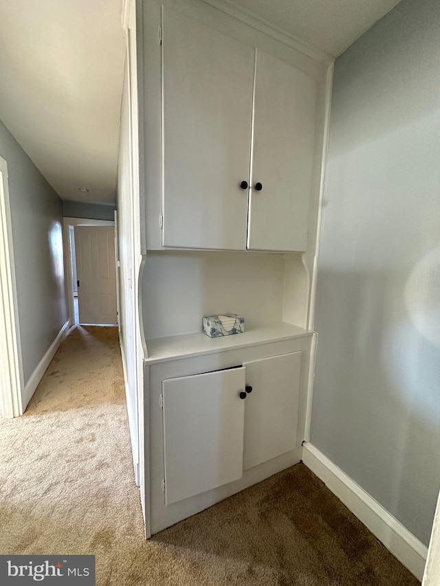 interior space featuring light colored carpet and baseboards