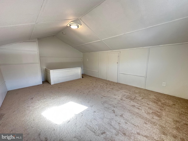 bonus room with vaulted ceiling and carpet floors