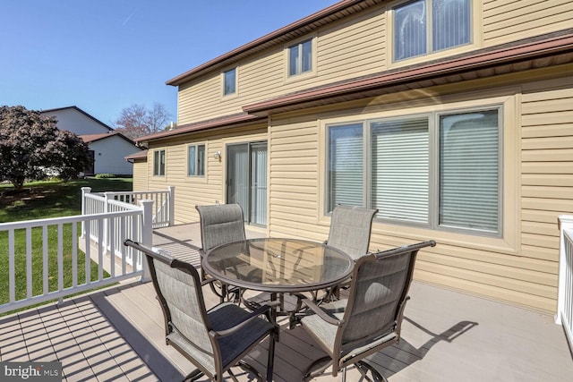 wooden terrace with outdoor dining area and a yard