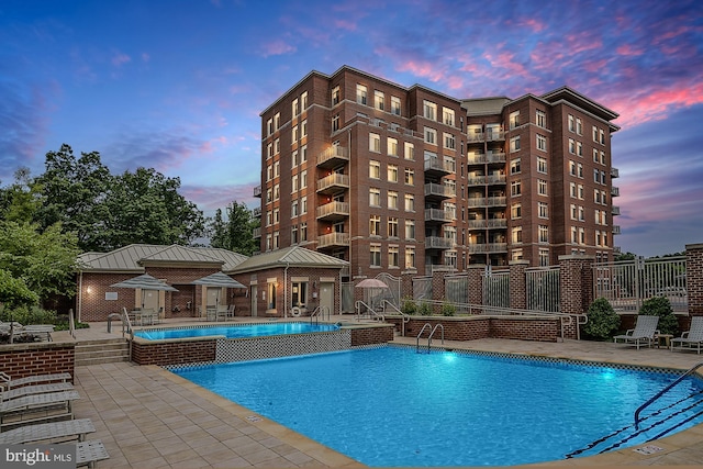 pool featuring a patio area, fence, an outdoor structure, and a storage structure