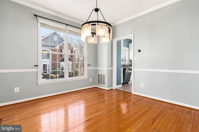 unfurnished dining area with baseboards, visible vents, hardwood / wood-style floors, crown molding, and a sink