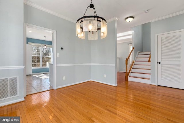 empty room featuring visible vents, crown molding, stairway, and hardwood / wood-style floors