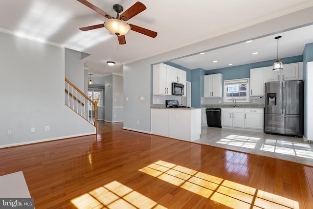 kitchen featuring light wood finished floors, stove, a sink, stainless steel fridge, and dishwasher