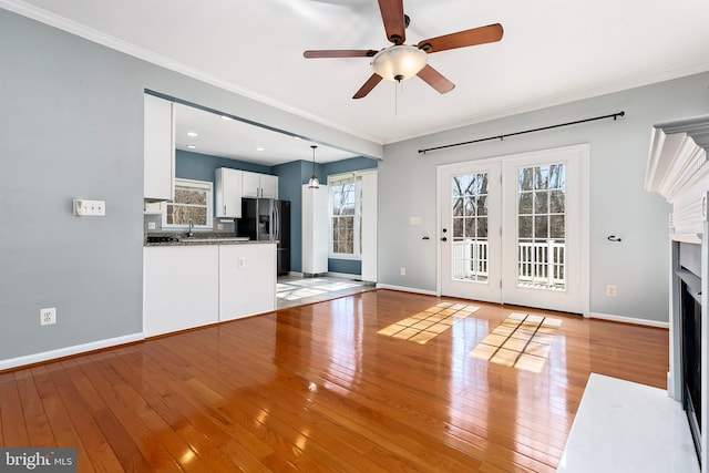 unfurnished living room with a fireplace with flush hearth, light wood-type flooring, and crown molding