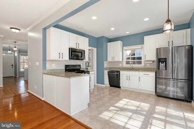 kitchen with tasteful backsplash, appliances with stainless steel finishes, white cabinets, a sink, and light stone countertops