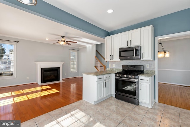 kitchen with light tile patterned floors, a fireplace with flush hearth, appliances with stainless steel finishes, and white cabinets