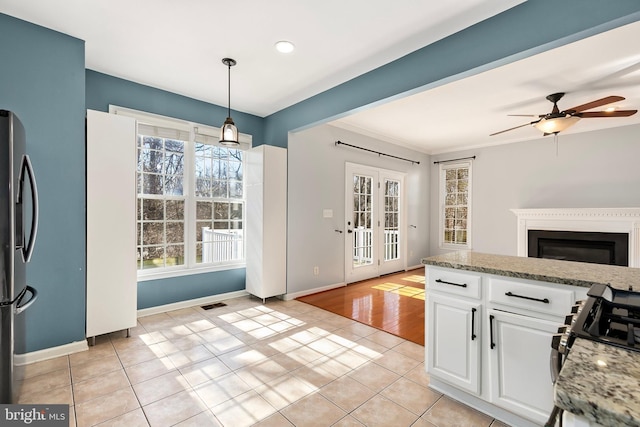 kitchen featuring light tile patterned floors, visible vents, white cabinets, stainless steel fridge with ice dispenser, and a glass covered fireplace