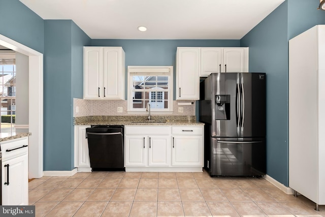 kitchen with dishwasher, light stone countertops, a healthy amount of sunlight, refrigerator with ice dispenser, and a sink