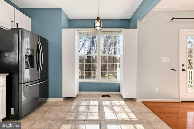 interior space with light tile patterned floors, visible vents, baseboards, white cabinetry, and stainless steel refrigerator with ice dispenser