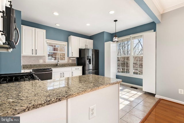 kitchen with stainless steel appliances, white cabinets, a sink, light stone countertops, and a peninsula