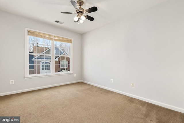 carpeted empty room featuring a ceiling fan, visible vents, and baseboards