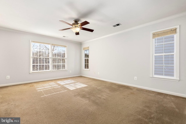 carpeted spare room with crown molding, ceiling fan, visible vents, and baseboards