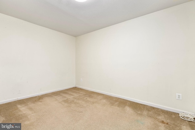 unfurnished room with light carpet and baseboards