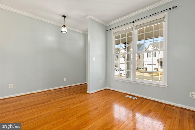 unfurnished room with wood-type flooring, visible vents, crown molding, and baseboards