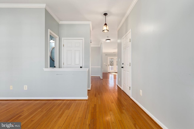 hallway with crown molding, hardwood / wood-style floors, stacked washing maching and dryer, and baseboards