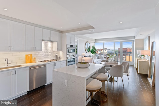 kitchen with a center island, a city view, stainless steel appliances, white cabinets, and a sink