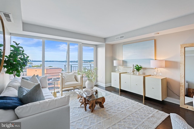 living room featuring a water view, dark wood finished floors, visible vents, and baseboards