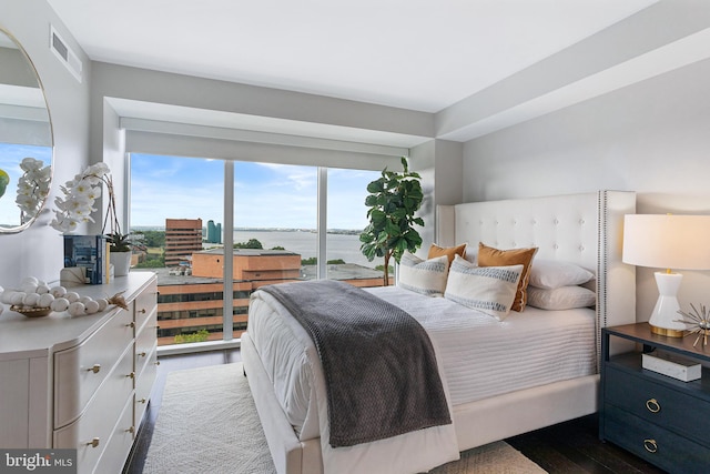 bedroom with a water view, visible vents, and wood finished floors