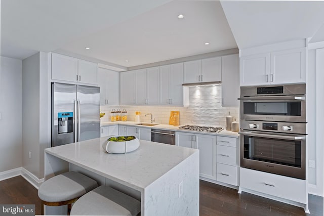 kitchen featuring light stone countertops, appliances with stainless steel finishes, white cabinets, and a center island