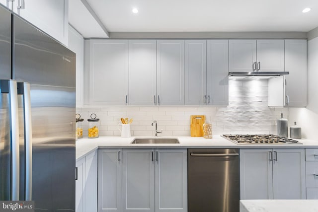 kitchen with a sink, backsplash, stainless steel appliances, and light countertops