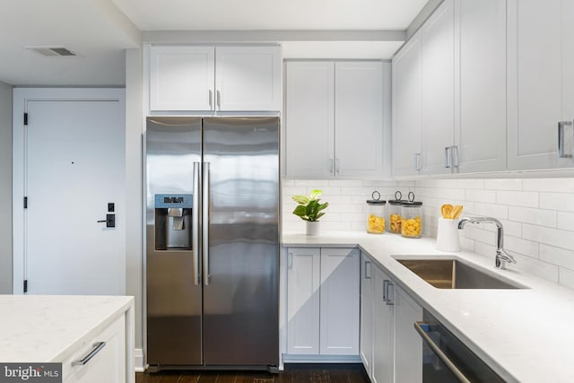 kitchen with visible vents, a sink, stainless steel appliances, white cabinetry, and backsplash