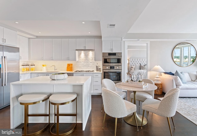 kitchen featuring stainless steel appliances, a kitchen island, visible vents, white cabinetry, and light countertops