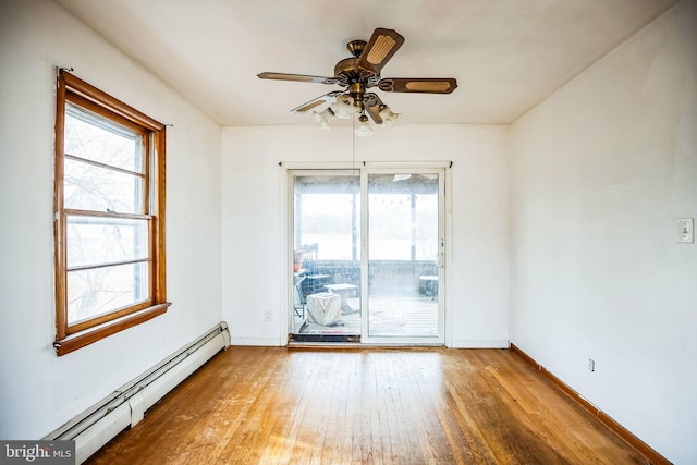 unfurnished room with a baseboard heating unit, a wealth of natural light, ceiling fan, and hardwood / wood-style flooring