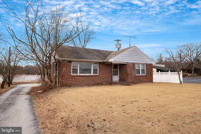 view of front of home with fence, a front lawn, and brick siding