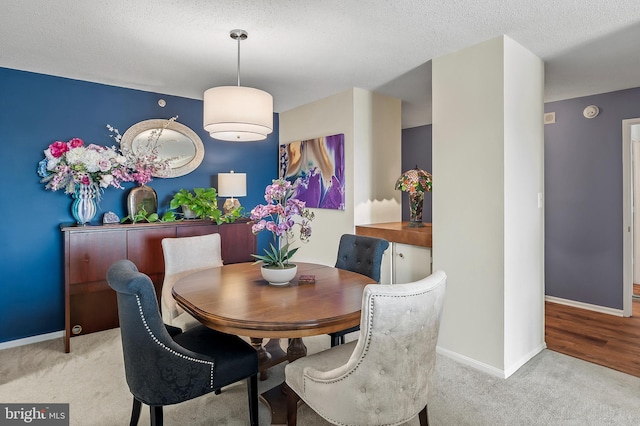 carpeted dining room with a textured ceiling and baseboards