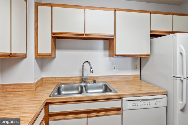 kitchen with white appliances, light countertops, a sink, and white cabinetry