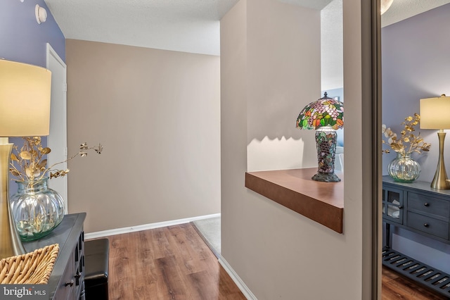 corridor with wood finished floors and baseboards