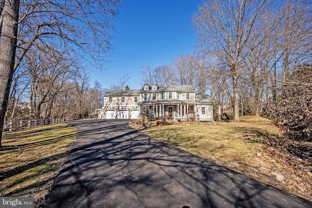 view of front of property with covered porch, driveway, and a front lawn