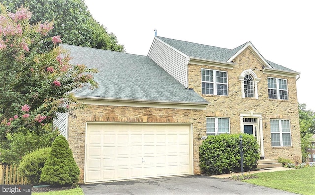 colonial home featuring a garage, brick siding, and a shingled roof