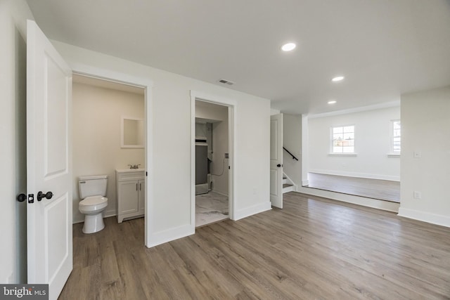 interior space featuring ensuite bath, visible vents, wood finished floors, and recessed lighting