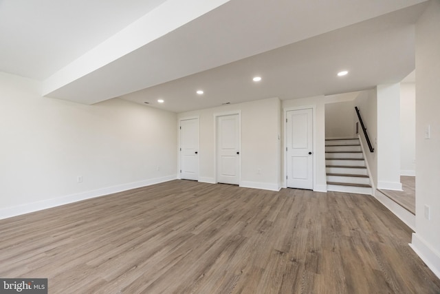 finished below grade area featuring recessed lighting, stairway, baseboards, and wood finished floors