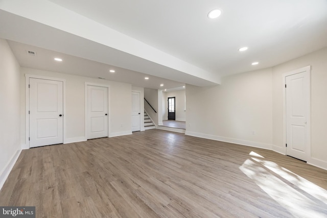 below grade area with stairs, light wood-type flooring, baseboards, and recessed lighting