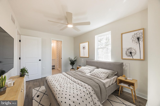 bedroom featuring visible vents, a ceiling fan, ensuite bath, wood finished floors, and baseboards