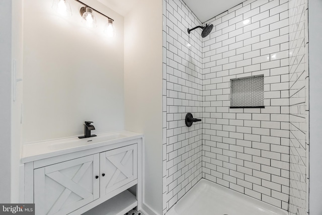 bathroom with a tile shower and vanity