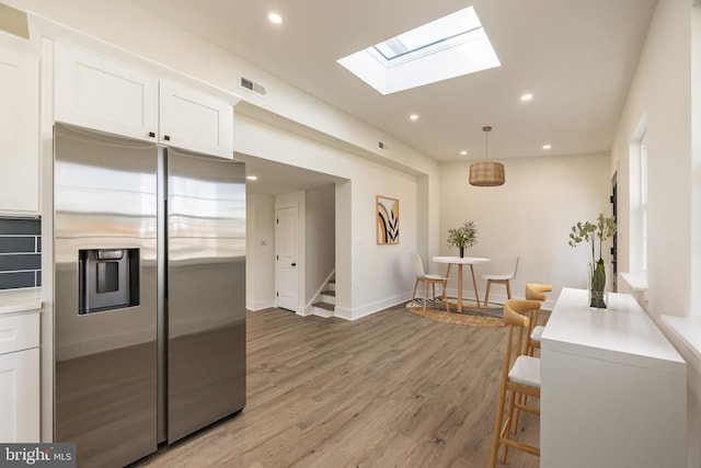 kitchen with recessed lighting, visible vents, light wood-style floors, white cabinets, and stainless steel fridge