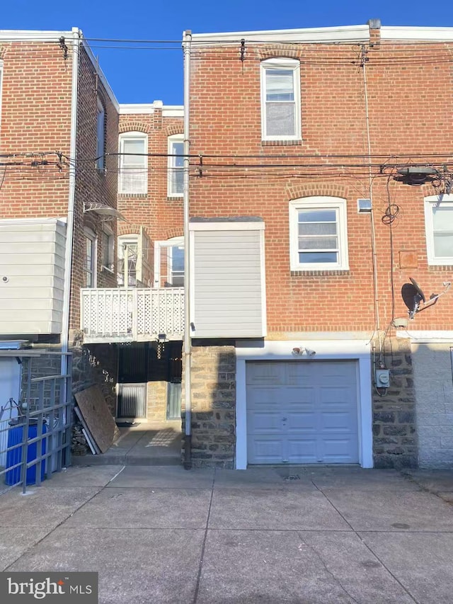 exterior space featuring a garage, driveway, brick siding, and stone siding