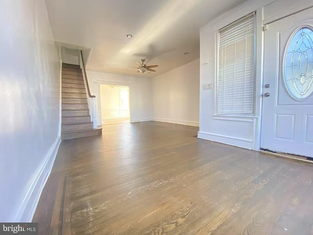 foyer entrance with dark wood-style flooring, stairway, and baseboards