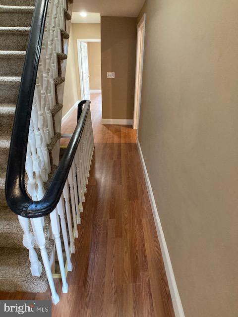 hallway with stairway, baseboards, and wood finished floors