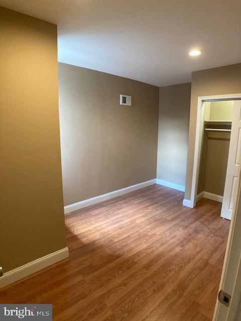 unfurnished bedroom with visible vents, baseboards, and wood finished floors