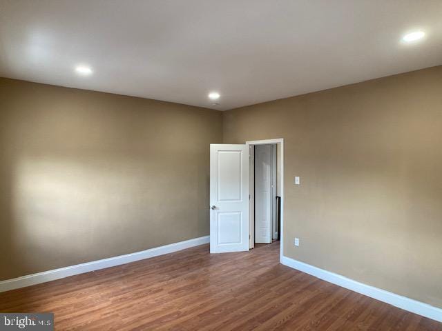 spare room with baseboards, wood finished floors, and recessed lighting