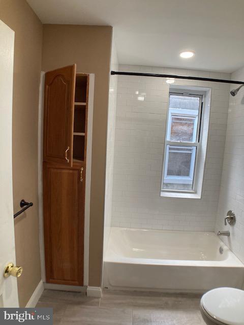 full bathroom with shower / bath combination, toilet, and baseboards