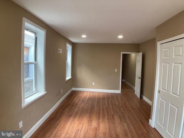 spare room with dark wood-style floors, a wealth of natural light, baseboards, and recessed lighting