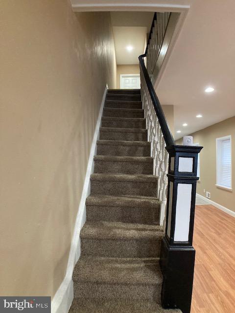 staircase featuring visible vents, baseboards, wood finished floors, and recessed lighting