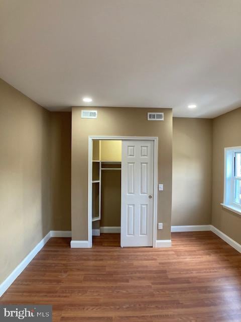 unfurnished bedroom with baseboards, visible vents, and wood finished floors