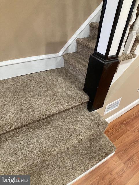 stairway featuring baseboards, visible vents, and wood finished floors